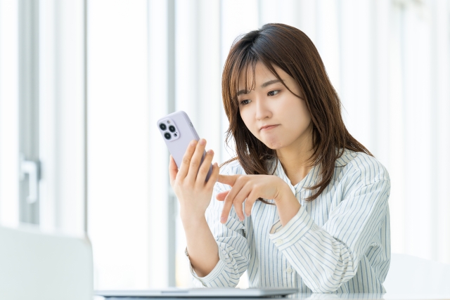 スマホを見ながら悩んだ表情をしている女性