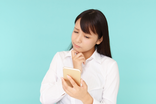 スマホを見て悩んでいる表情の女性