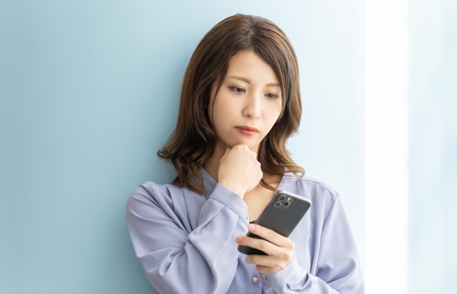 スマホを見つめながら悩んだ表情の女性