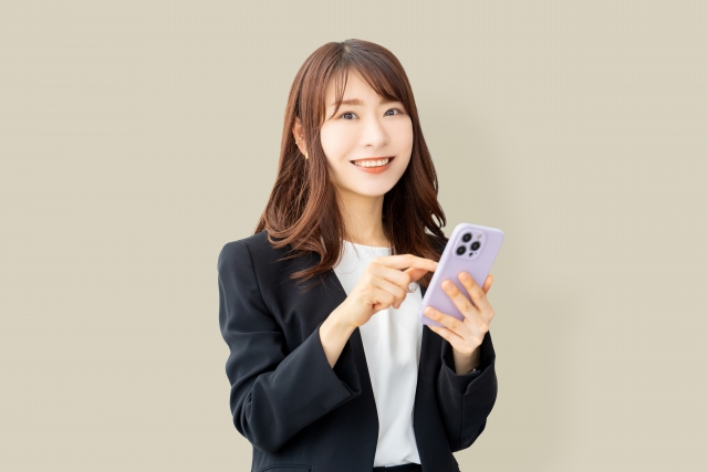 スマホを手に持ち笑顔の女性