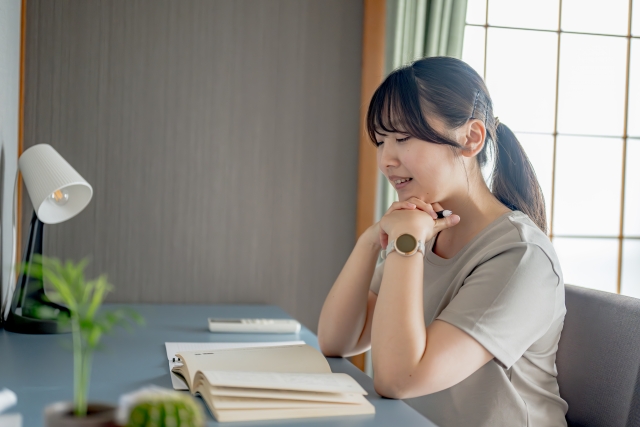 机に肘をついて考えている仕草の女性