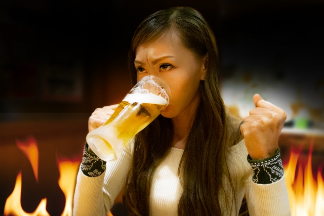 ビールを飲みながら闘志を燃やしている様子の女性の画像